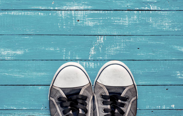 istock Blue men's old shabby sneakers on a blue wooden surface 653365244