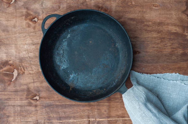 istock Black cast-iron empty frying pan on a brown wooden surface 653367544