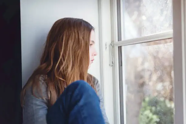 Photo of Candid Portrait of a Lonely Twelve Year Old Girl Gazing Out Of a Window