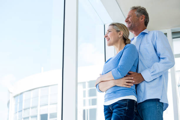 istock Couple looking through window at home 653372522