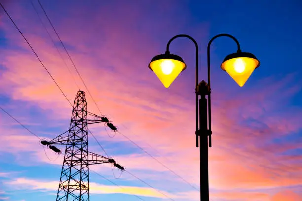 lit on streetlamp at sunset with high-tension line and pylon on the background