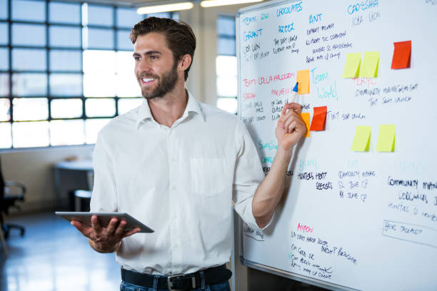 istock Smiling businessman pointing on whiteboard 653375098