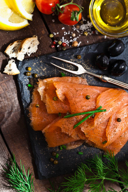 Smoked salmon Top view of a slate tray with smoked salmon on rustic wood table. DSRL studio photo taken with Canon EOS 5D Mk II and Canon EF 100mm f/2.8L Macro IS USM smoked salmon stock pictures, royalty-free photos & images