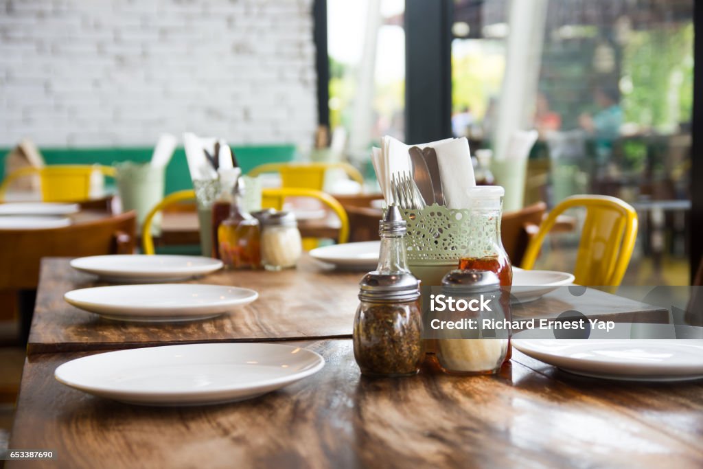 table setup setup wooden table, plates, utensils, and condiments Restaurant Stock Photo