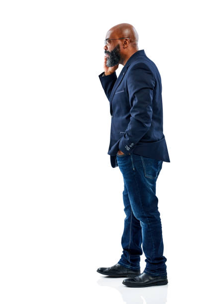 Full length side portrait of african businessman talking on mobile phone while standing over white background