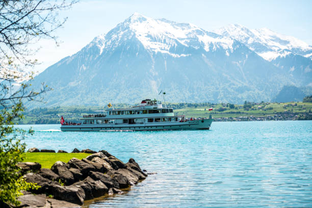 Interlaken, Switzerland - May 5, 2014: Ferry with passengers and Swiss Flag on Lake Thun with Swiss Alps on background