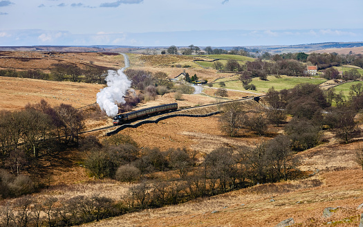 Goathland, Yorkshire, UK. A vintage steam train chuggs through the North York Moors national park on a fine springh morning near Goathland, Yorkshire, UK.