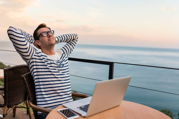 istock Software development manager taking a break from his work, magnificent view of the sea, lake, river in the background 653423856