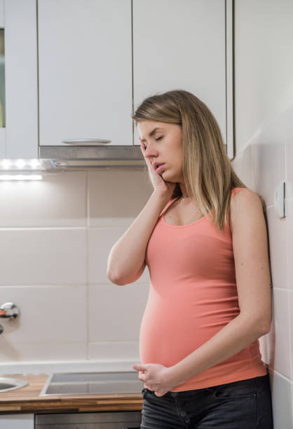 istock Pregnant woman with hand on forehead suffering headache . 653423892