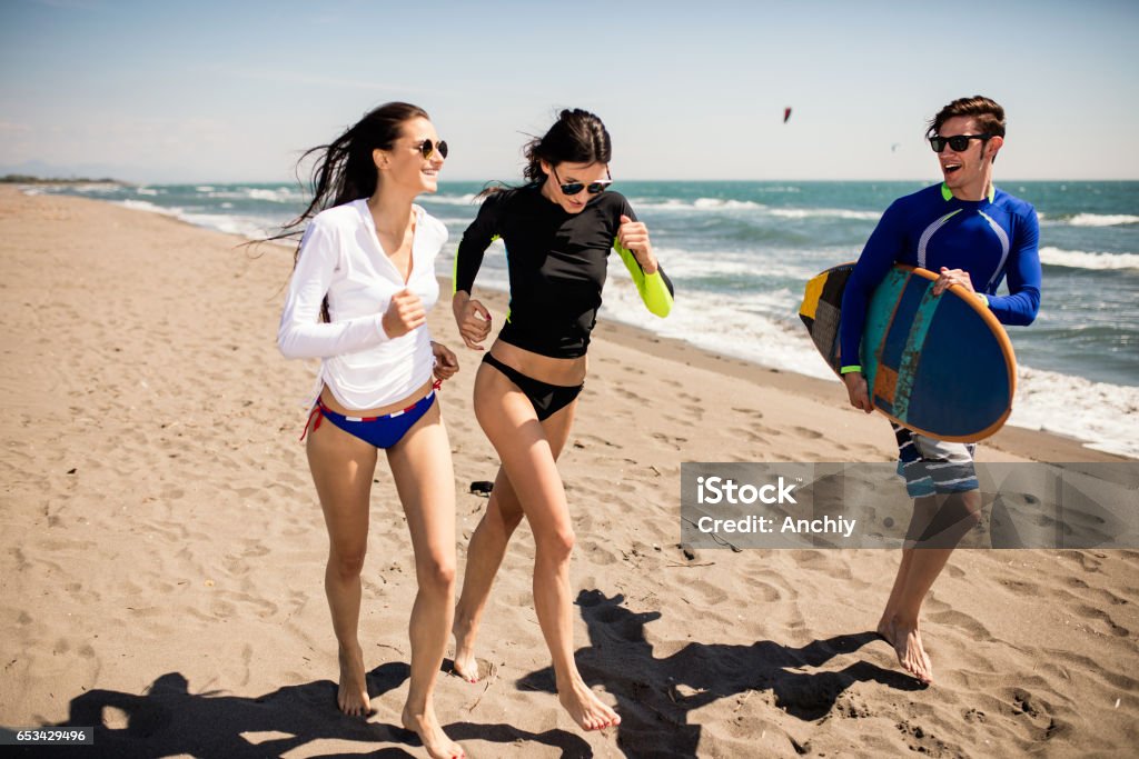 Surfers running to the ocean. Happy friends with surfboard 20-29 Years Stock Photo