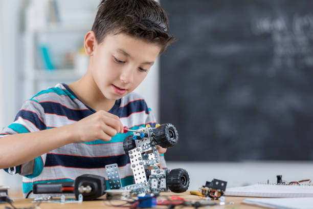 istock Schoolboy concentrates as he builds a robotic vehicle 653433008
