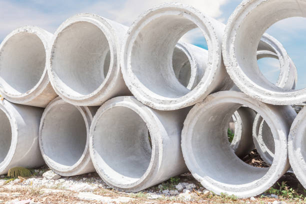 istock Pile of big concrete drainage pipes with construction site background. 653446646