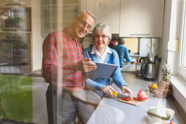 istock Cheerful senior couple preparing healthy meal using online recipe 653446732