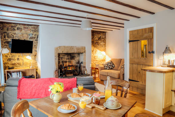 Log Cabin Living Room Interior shot of a log cabin living room. There are breakfast croissants and juice on the dining table modern cottage interior design stock pictures, royalty-free photos & images