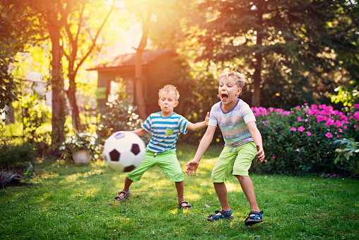 Little boys aged 7 are playing football in the garden.\n