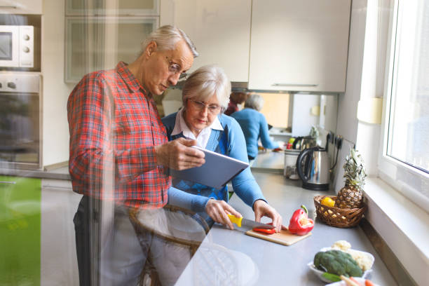 istock Cheerful senior couple preparing healthy meal using online recipe 653447518