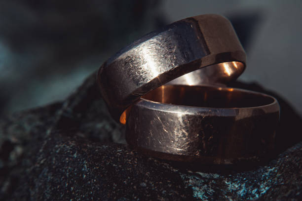 istock scratched two wide gold wedding rings on stone surface 653448152