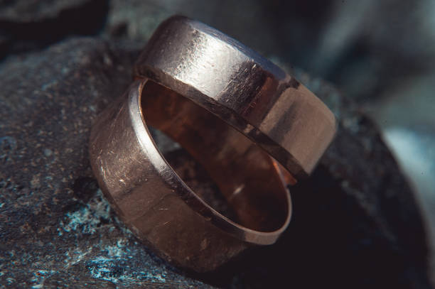 istock scratched two wide gold wedding rings on stone surface 653448296