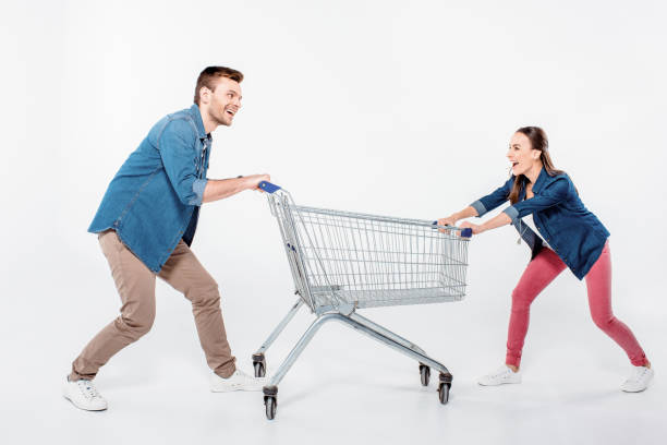 istock smiling couple pulling empty shopping cart and looking on each other on white 653453470