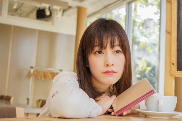 istock Young woman reading a book at cafeteria 653453572