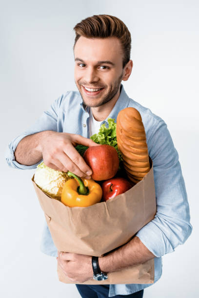 istock Handsome young man holding grocery bag and smiling at camera 653460736