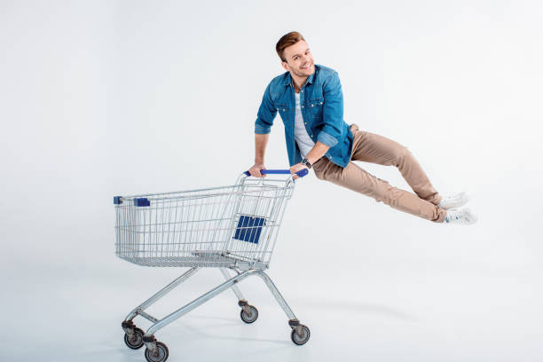 istock Excited young man jumping and having fun with shopping trolley on white 653463450