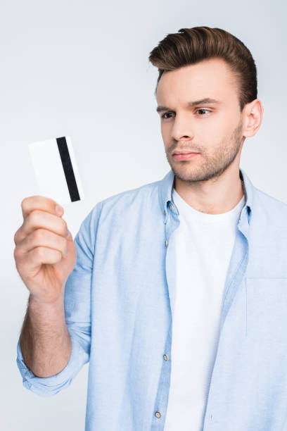 istock Handsome young man holding credit card in hand on white 653464082