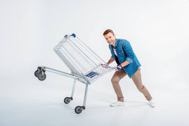 istock Excited young man having fun with shopping trolley on white 653464728