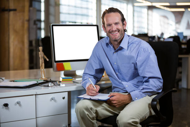 istock Businessman writing on clipboard by desk 653466916