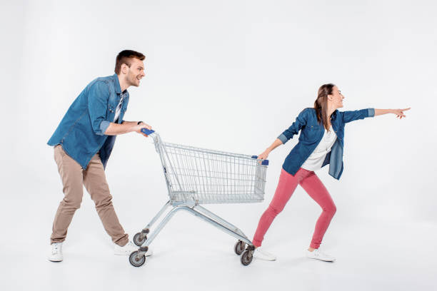 istock woman pointing way and while pulling shopping cart with man on white 653467114