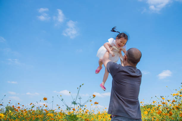 istock girl smiling between her father throw her to the air 653468238
