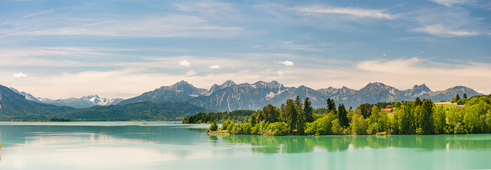 Panorama scene in Bavaria, Germany, with alps mountains mirroring in lake nearby city Fuessen in region Allgaeu