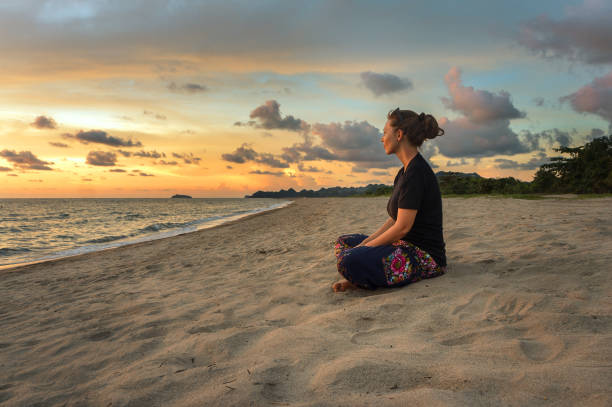 mulher relaxante na praia ao pôr do sol - bodies of water people yoga horizontal - fotografias e filmes do acervo