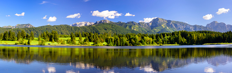 Panorama scene in Bavaria, Germany, with alps mountains mirroring in lake nearby city Fuessen in region Allgaeu