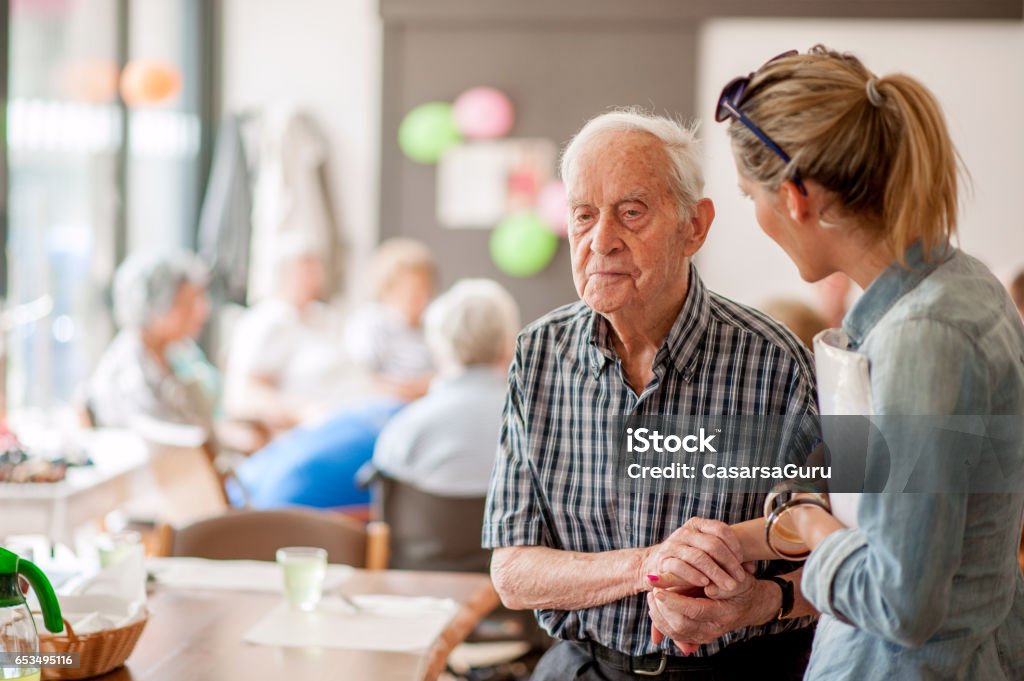 Assistant In The Community Center Giving Advice To A Senior Man Dementia Stock Photo