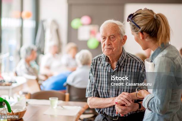 Assistant In The Community Center Giving Advice To A Senior Man Stock Photo - Download Image Now