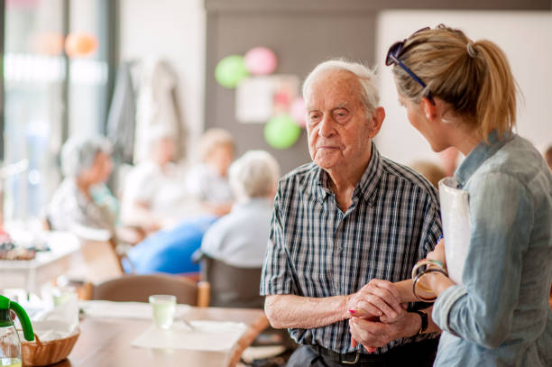 asystent w centrum społeczności udzielając porad starszemu mężczyźnie - help assistance support dependency zdjęcia i obrazy z banku zdjęć