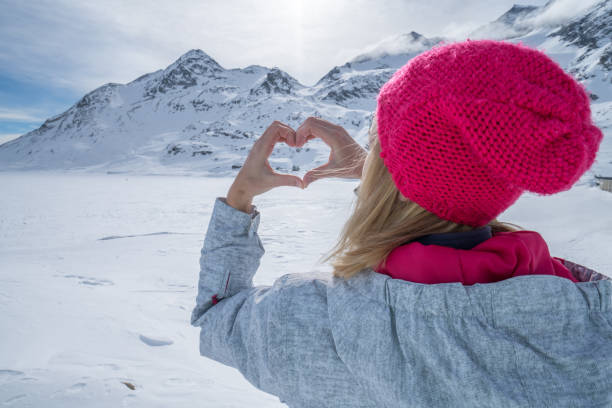 istock Young woman on ski slopes making heart shape 653503492