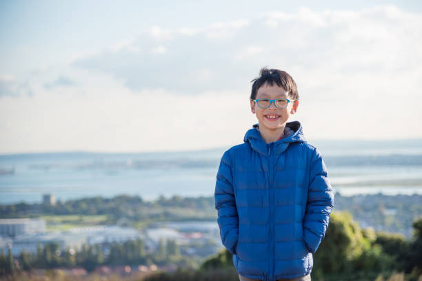 Young asian boy wearing blue jacket and smiles