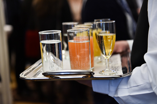 Waiter holding a tray with champagne glasses and other beverages during a cocktail event