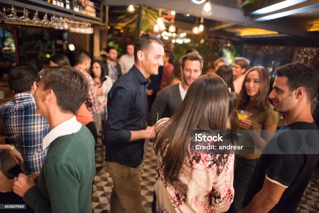 Friends having drinks at a bar Group of friends having drinks at a bar and looking very happy - night out concepts Cocktail Party Stock Photo