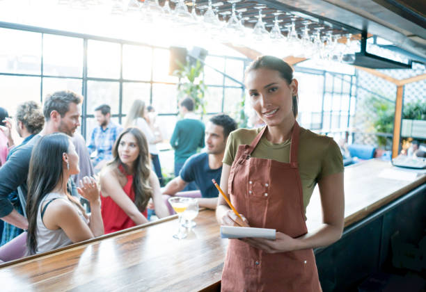 istock Waitress working at a bar looking at the camera smiling 653507642