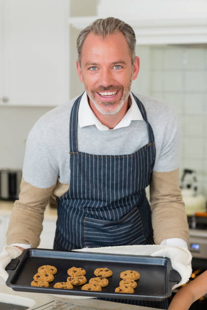 istock Man holding a cookies in baking tray at kitchen 653514058