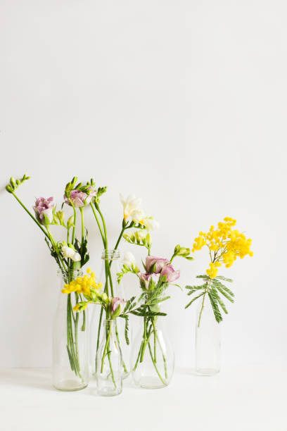 istock Stilllife of spring flowers in transparent bottles on white table 653514234