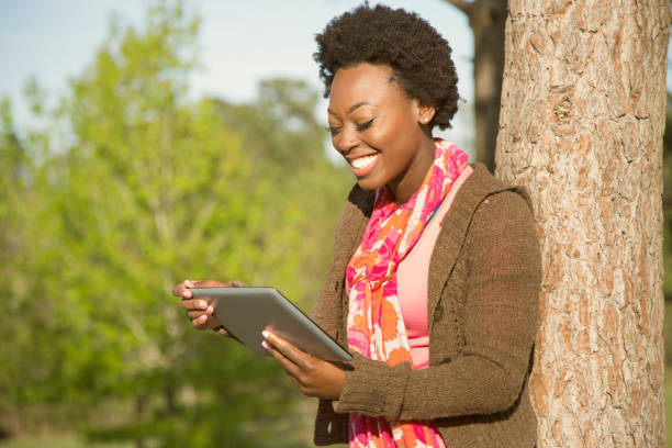 istock One African descent woman using digital tablet outdoors in park. 653520868
