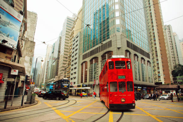 Hong Kong - February 12, 2016: Motion of red double-decker tram on street with huse modern buildings on February 12, 2016. Hong Kong dollar is the eighth most traded currency in the world.