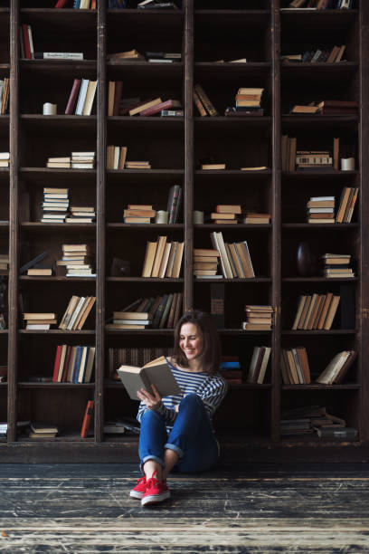 istock Happy young woman reading in the library 653532794