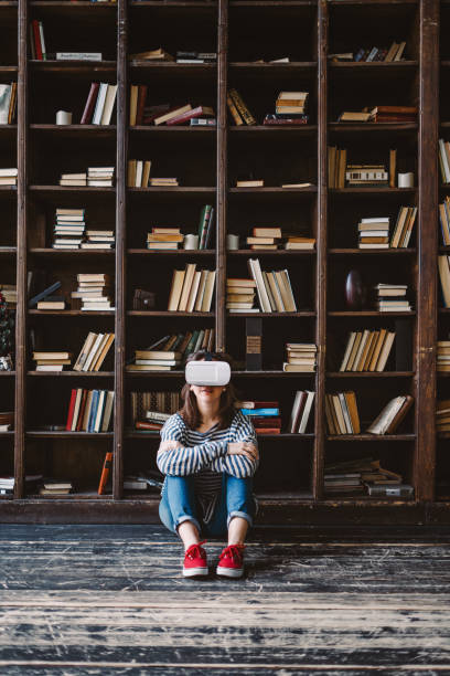 istock Young woman choosing VR Glasses over books 653532796