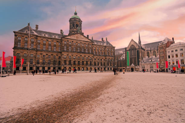 verschneite dam in amsterdam niederlande im winter bei sonnenuntergang - dam stock-fotos und bilder