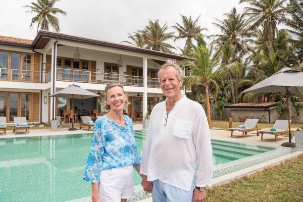 istock Senior couple holding hands by swimming pool on vacation 653532940